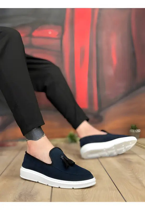 Navy blue slip-on sneaker with white sole and tassel detail.