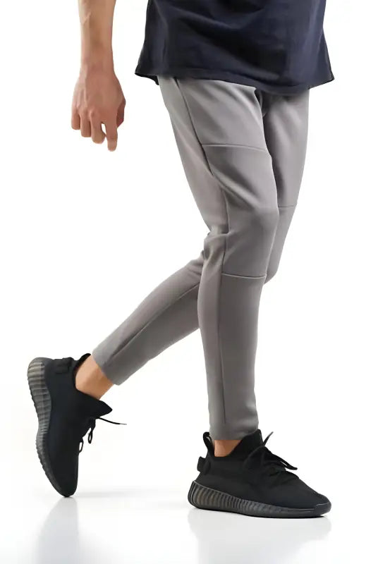 Light gray tapered jogger pants with black sneakers.