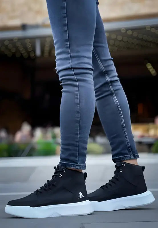 Black high-top sneakers with white soles paired with blue skinny jeans.