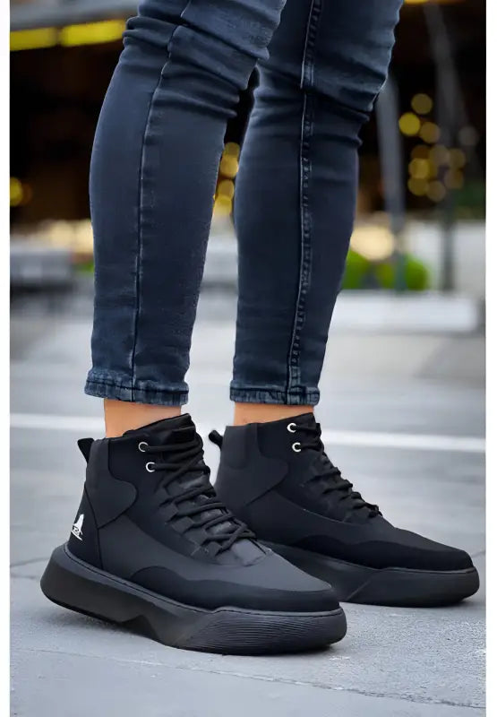 Black high-top sneakers with chunky soles worn with dark skinny jeans.