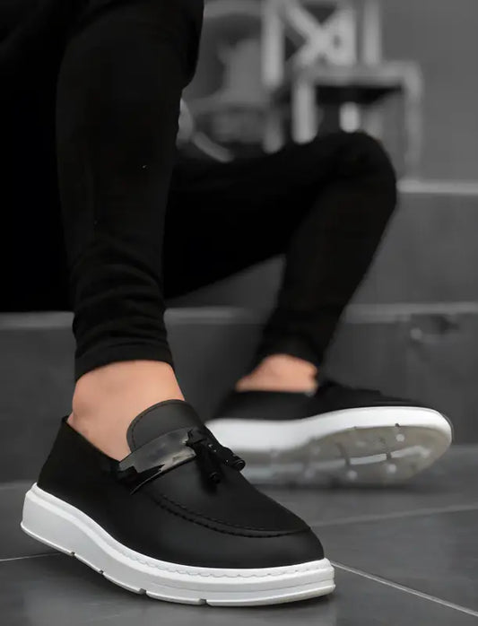 Black slip-on sneaker with white sole and decorative bow detail.