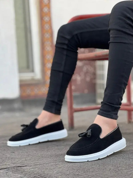 Black suede tassel loafers with white soles and a casual sneaker-like design.