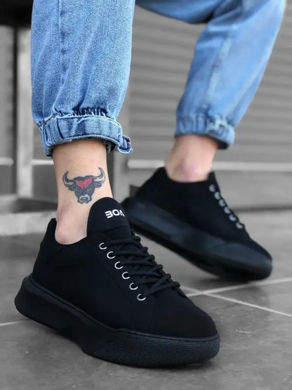 Black canvas sneakers with thick soles and white laces, worn with rolled-up jeans and a visible bull tattoo on the ankle.