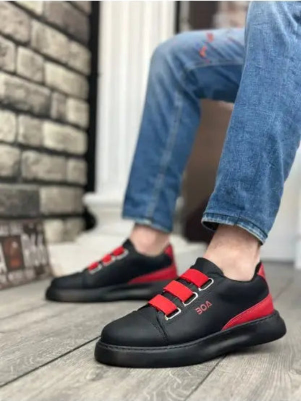 Black sneakers with red velcro straps and a chunky sole.