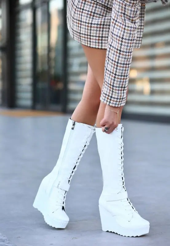 White platform lace-up boots with a tall shaft and chunky wedge sole.