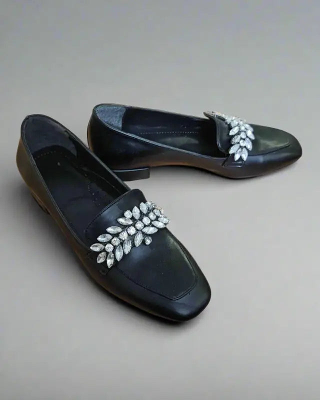 Black leather loafers decorated with crystal leaf embellishments on the upper.