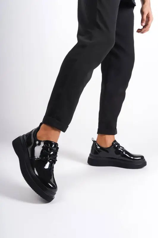 Shiny black patent leather platform sneakers with thick soles.