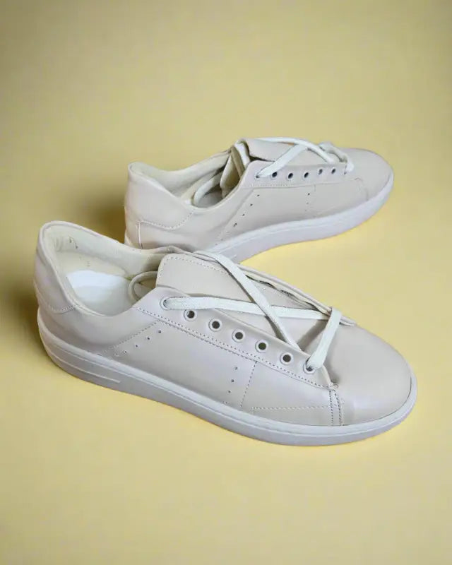 Pair of plain white leather sneakers with laces.