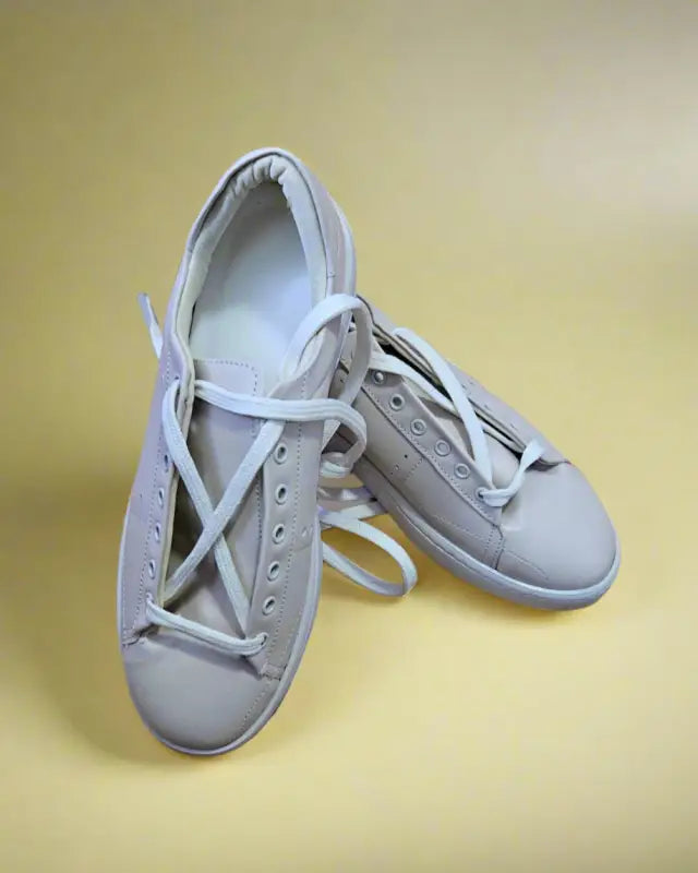 Pair of white leather sneakers with laces.