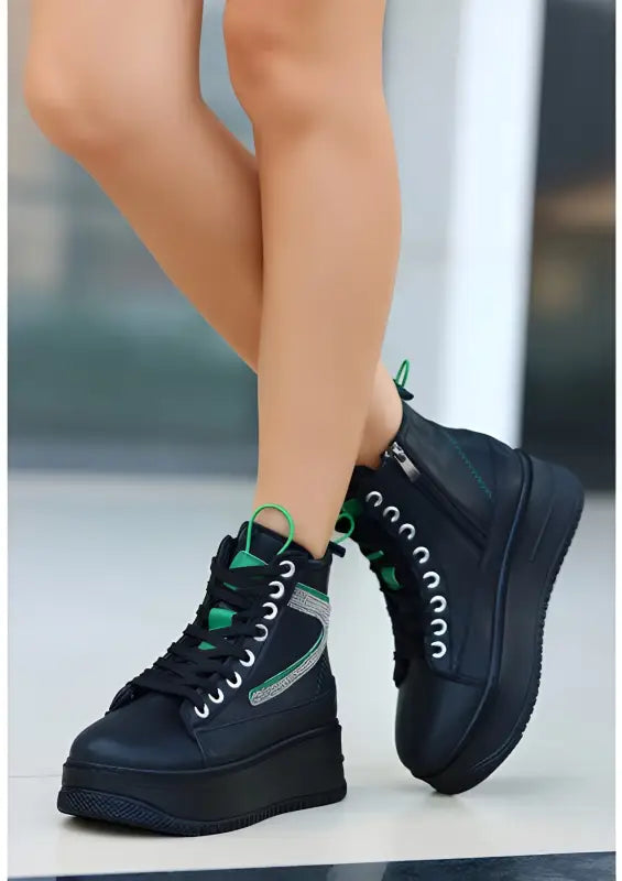 Black platform sneakers with green accents and white laces.