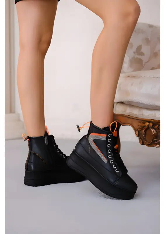 Black platform high-top sneakers with orange accents and laces.