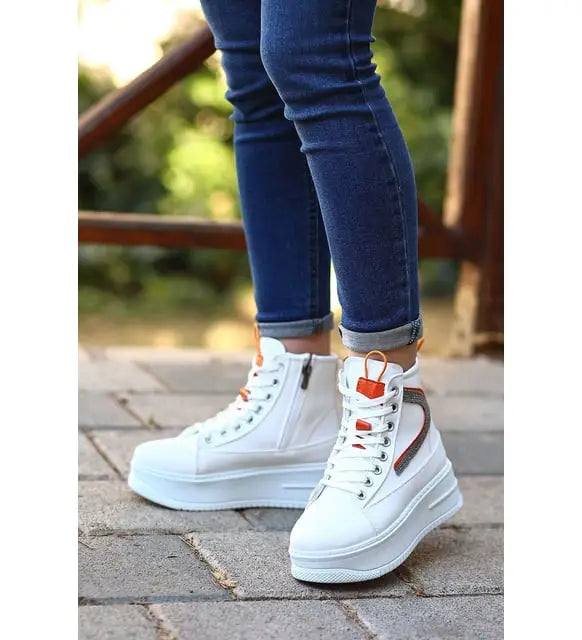 White high-top platform sneakers with side zippers and orange accents.