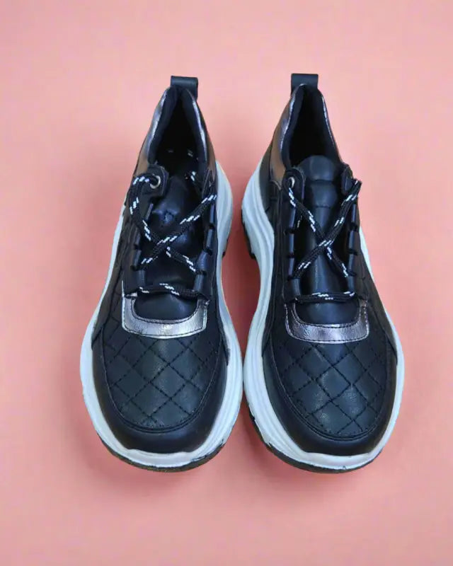 Black quilted sneakers with white soles and laces.