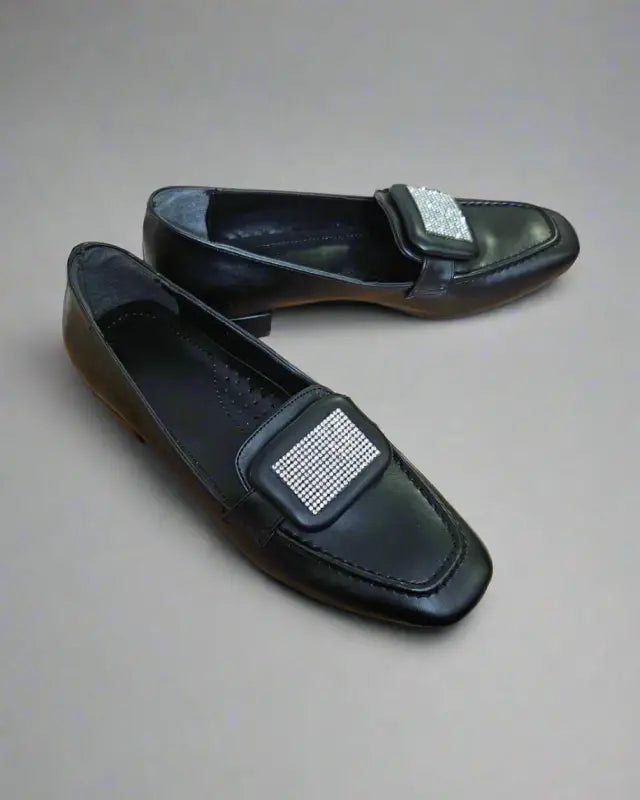 Black leather loafers with rhinestone embellishments on the upper.