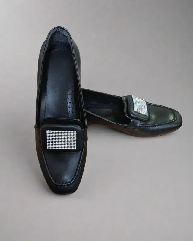 Black leather loafers with rhinestone embellishments on the vamp.