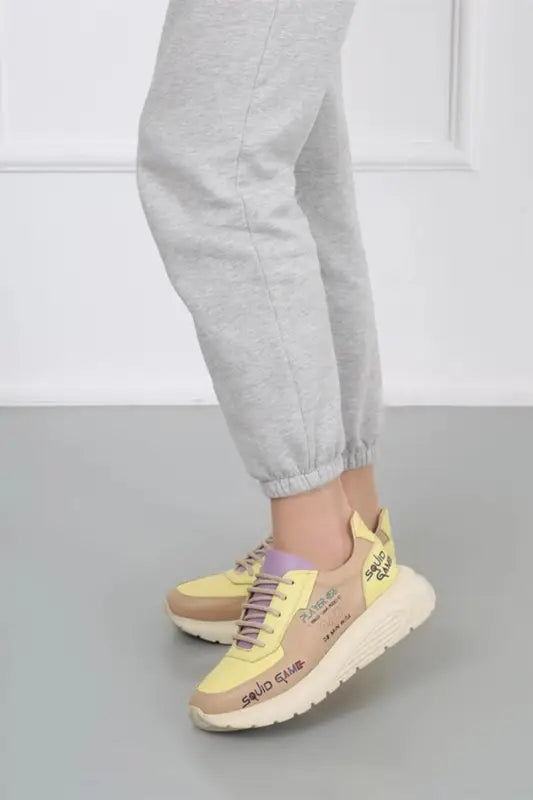 Yellow and beige chunky sneakers with platform soles and purple accents.