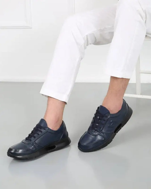 Navy blue leather sneakers with laces worn with white pants.