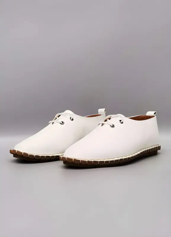 White leather lace-up shoes with brown rubber soles.