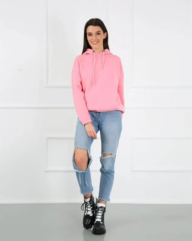 Pink cropped hoodie with distressed blue jeans and black combat boots.