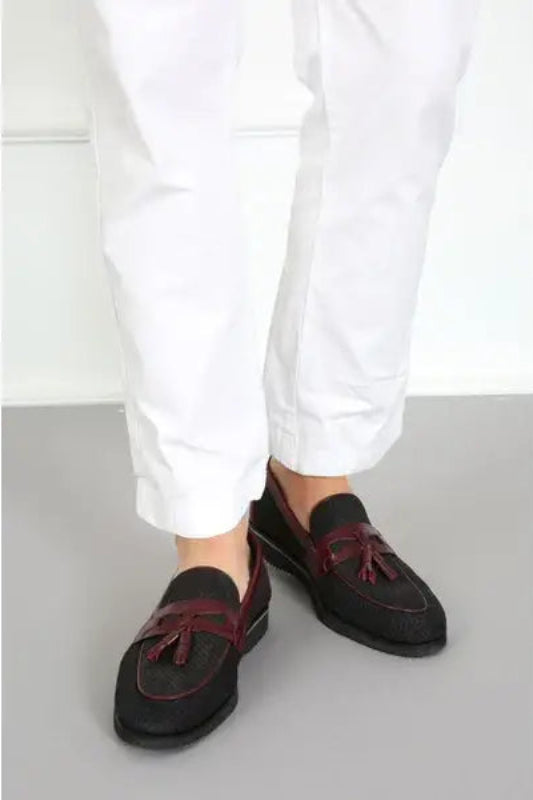 Dark suede loafers with burgundy tassels worn with white pants.