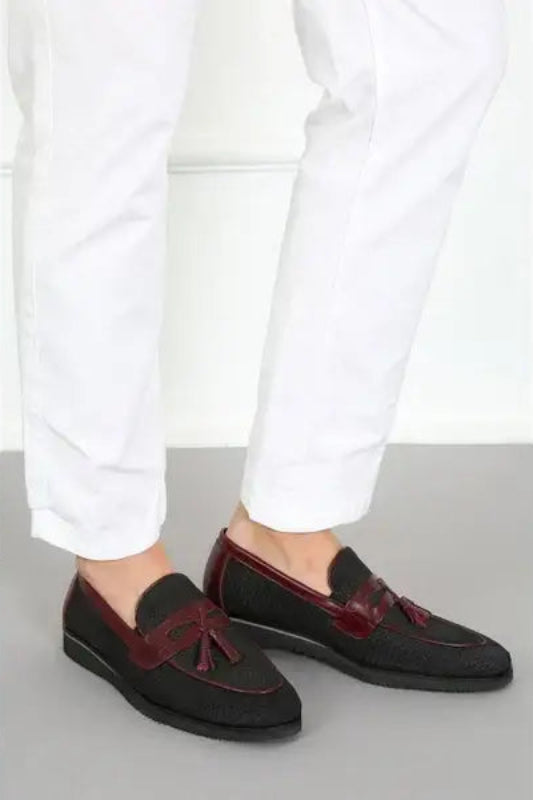 Burgundy and black suede tassel loafers with white pants visible above.