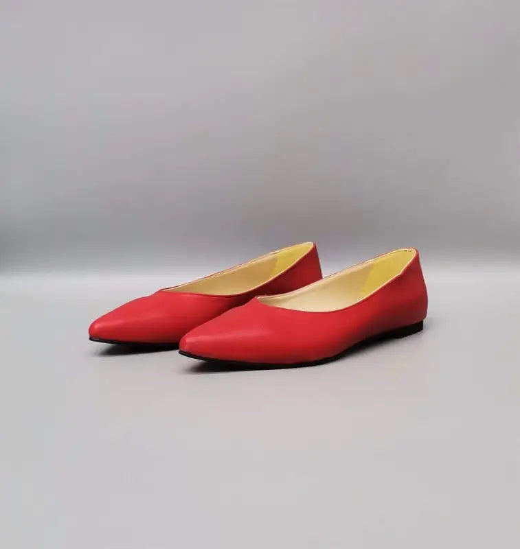 Red pointed-toe ballet flats with beige interior lining.