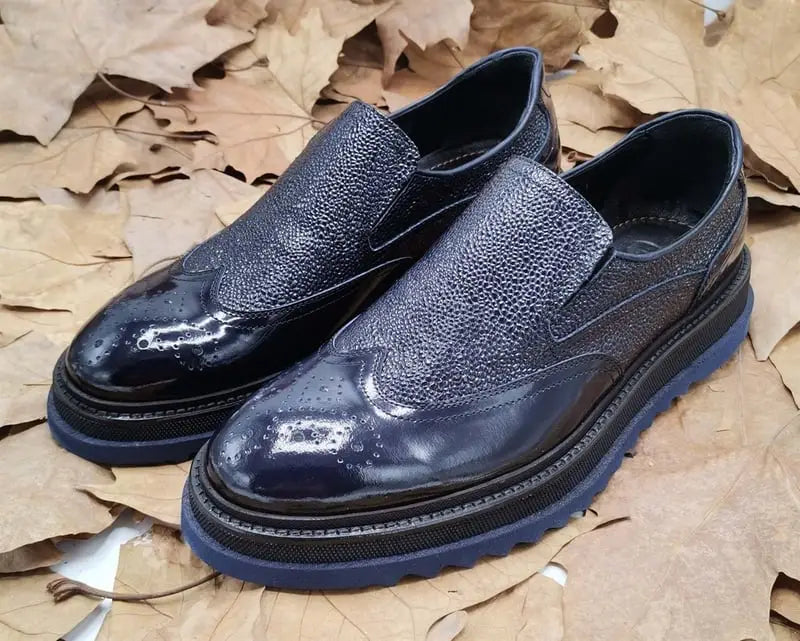 Navy blue leather slip-on dress shoes with textured uppers and thick rubber soles.