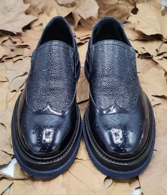 Black leather dress shoes with a textured wingtip pattern and thick soles.