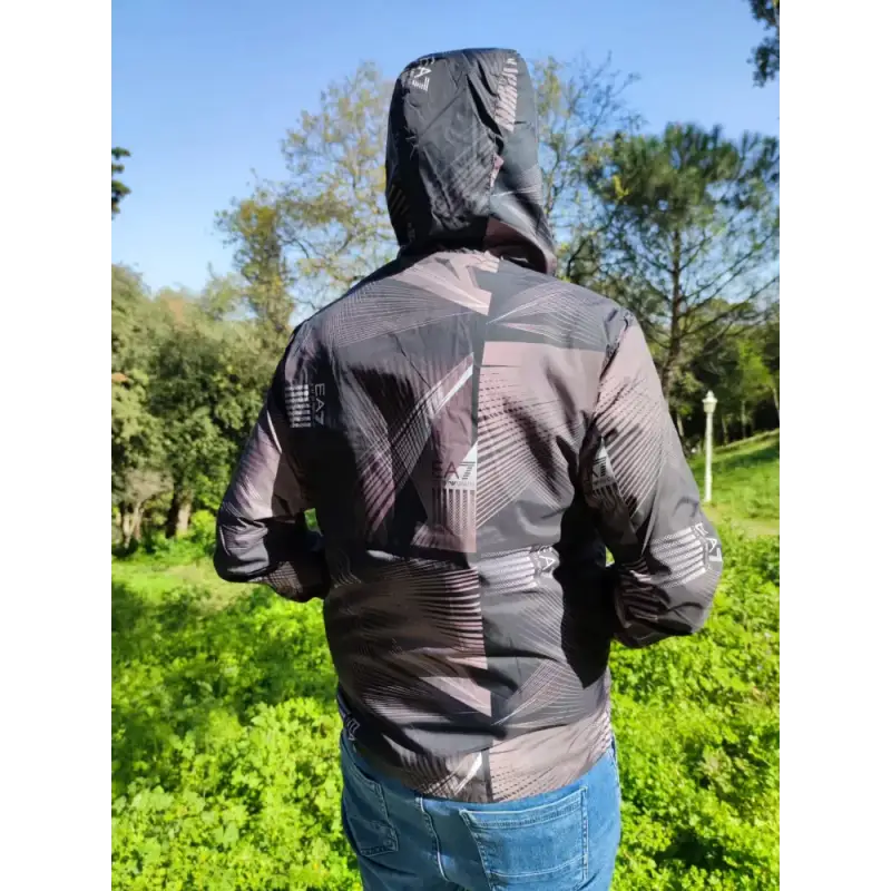 Black hooded jacket with geometric pattern designs worn by someone facing away from the camera.