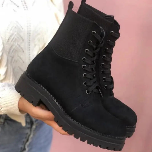 Black suede combat boot with chunky platform sole and lace-up design.