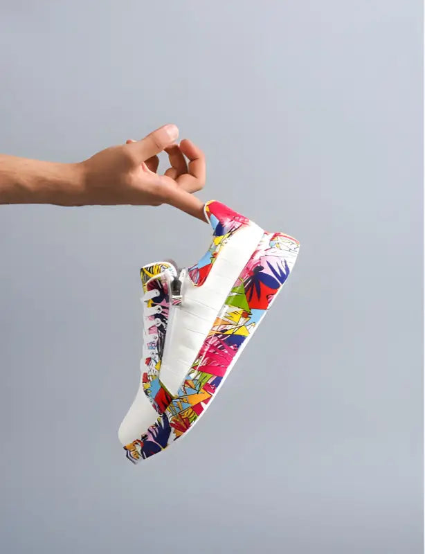 Colorful sneaker with vibrant graffiti-style artwork on its side being held by a hand.