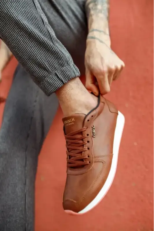 Brown leather sneaker with white sole and tan laces.