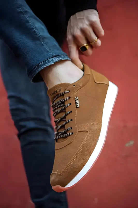 Brown leather sneaker with white sole and dark laces.