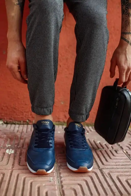 Navy blue sneakers with gum soles worn with pinstriped pants.