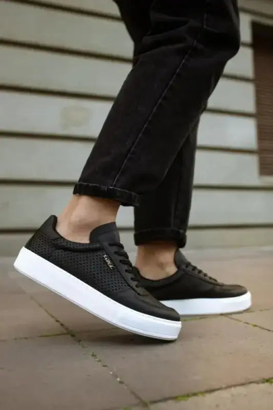 Black sneakers with perforated leather uppers and white soles.