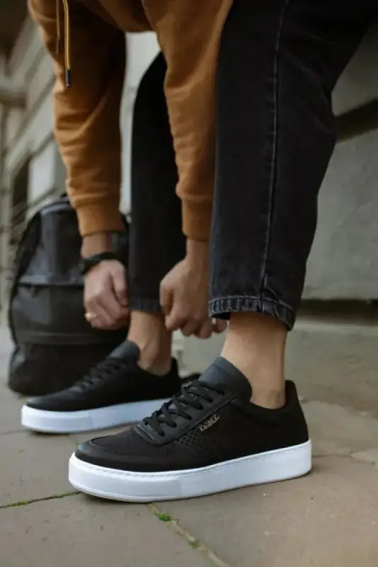 Black canvas sneakers with white soles and dark laces.