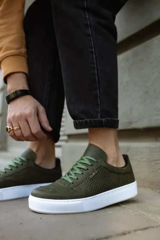 Olive green suede sneakers with white soles and matching laces.