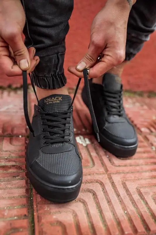 Black athletic sneakers with laces being tied on brick steps.