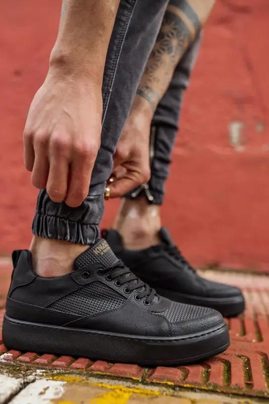 Black leather sneakers with mesh detailing and a chunky sole.