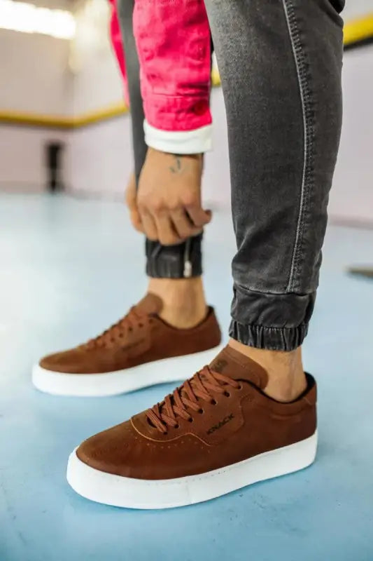 Brown suede sneakers with white soles and matching brown laces.