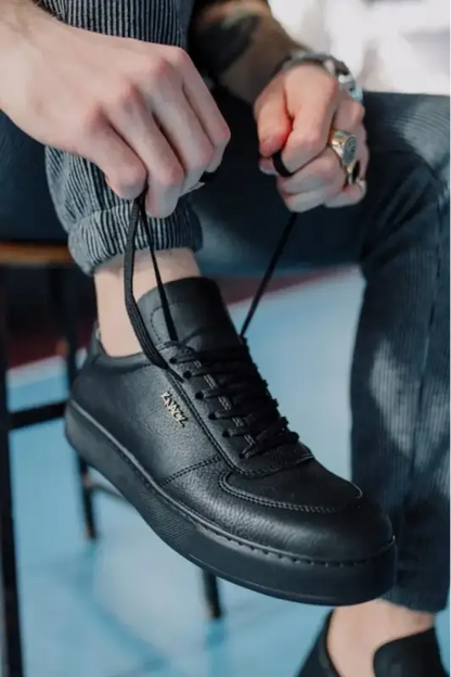 Black leather sneaker with thick soles and laces being tied.