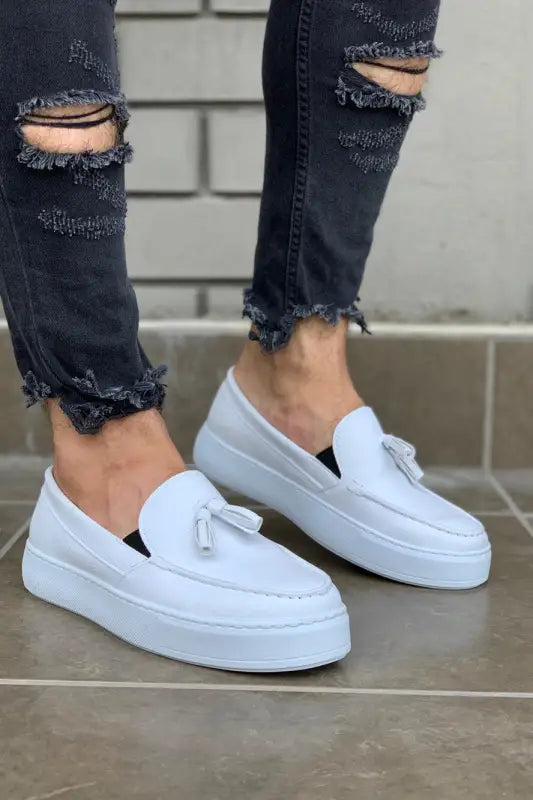 White leather platform loafers with decorative tassels.