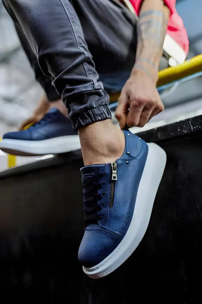 Navy blue leather sneaker with white sole and side zipper detail.