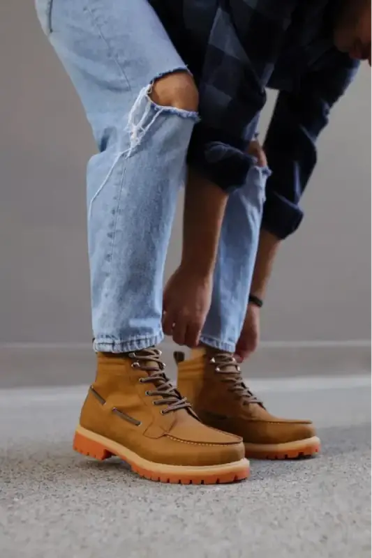 Tan leather work boots with orange rubber soles and brown laces.