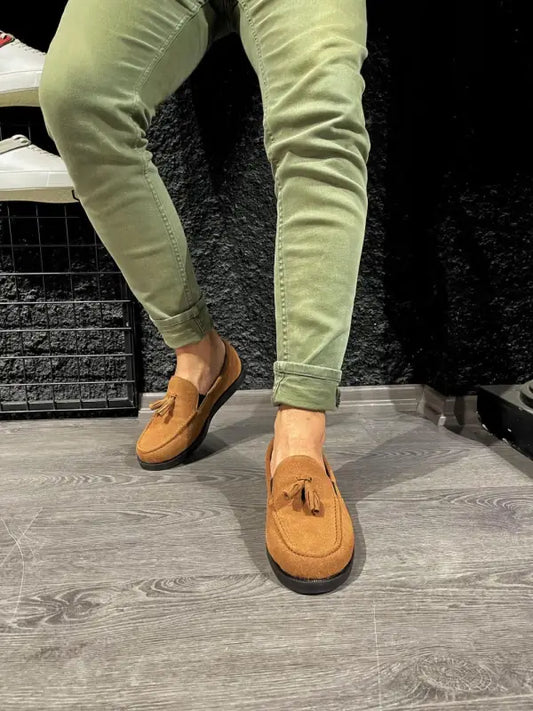 Tan suede loafers with tassels paired with light green pants.