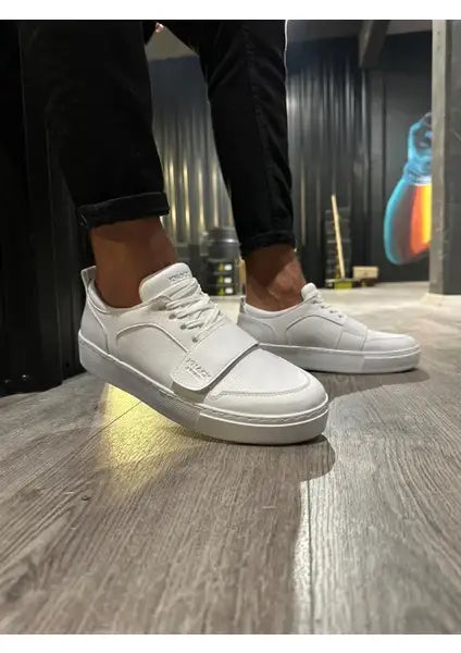 White leather sneakers with laces on feet.