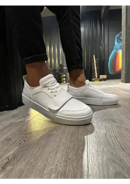 White leather sneakers with laces on feet.