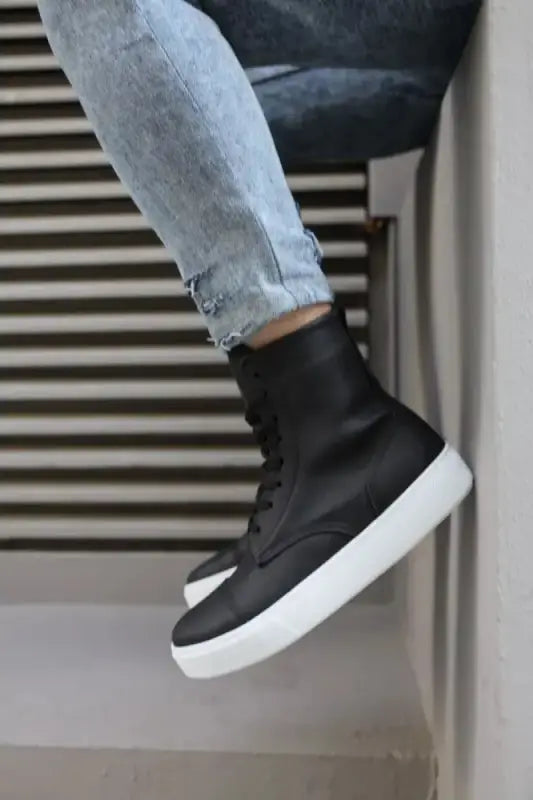 Black high-top sneaker with a white sole and distressed light blue jeans.