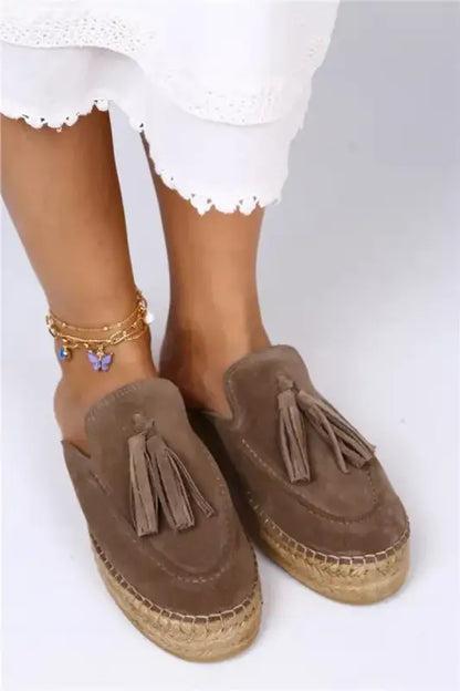 Brown suede espadrille mules with decorative tassels.