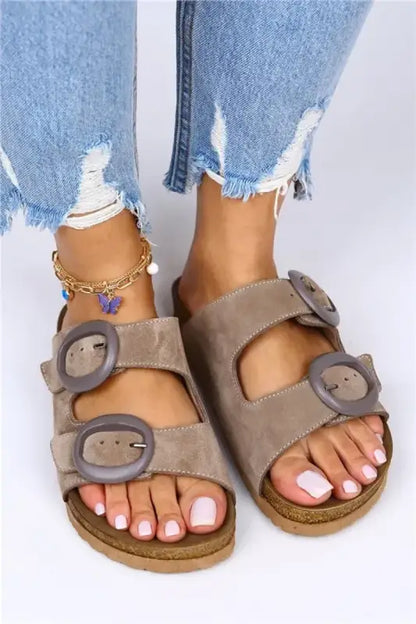 Taupe suede sandals with buckle straps and a cork footbed.